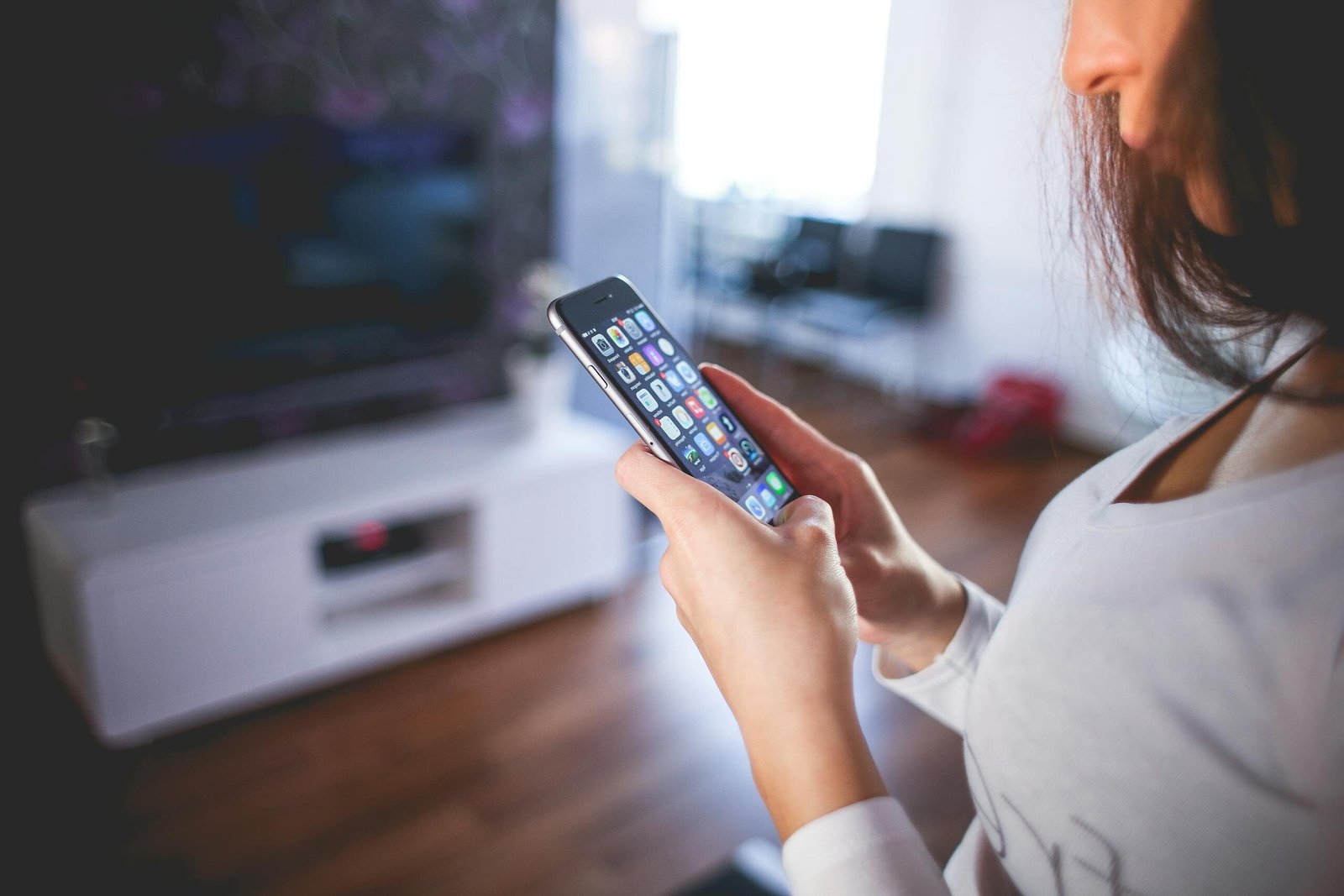 Woman browsing smartphone indoors, highlighting modern technology and communication in a cozy home setting.